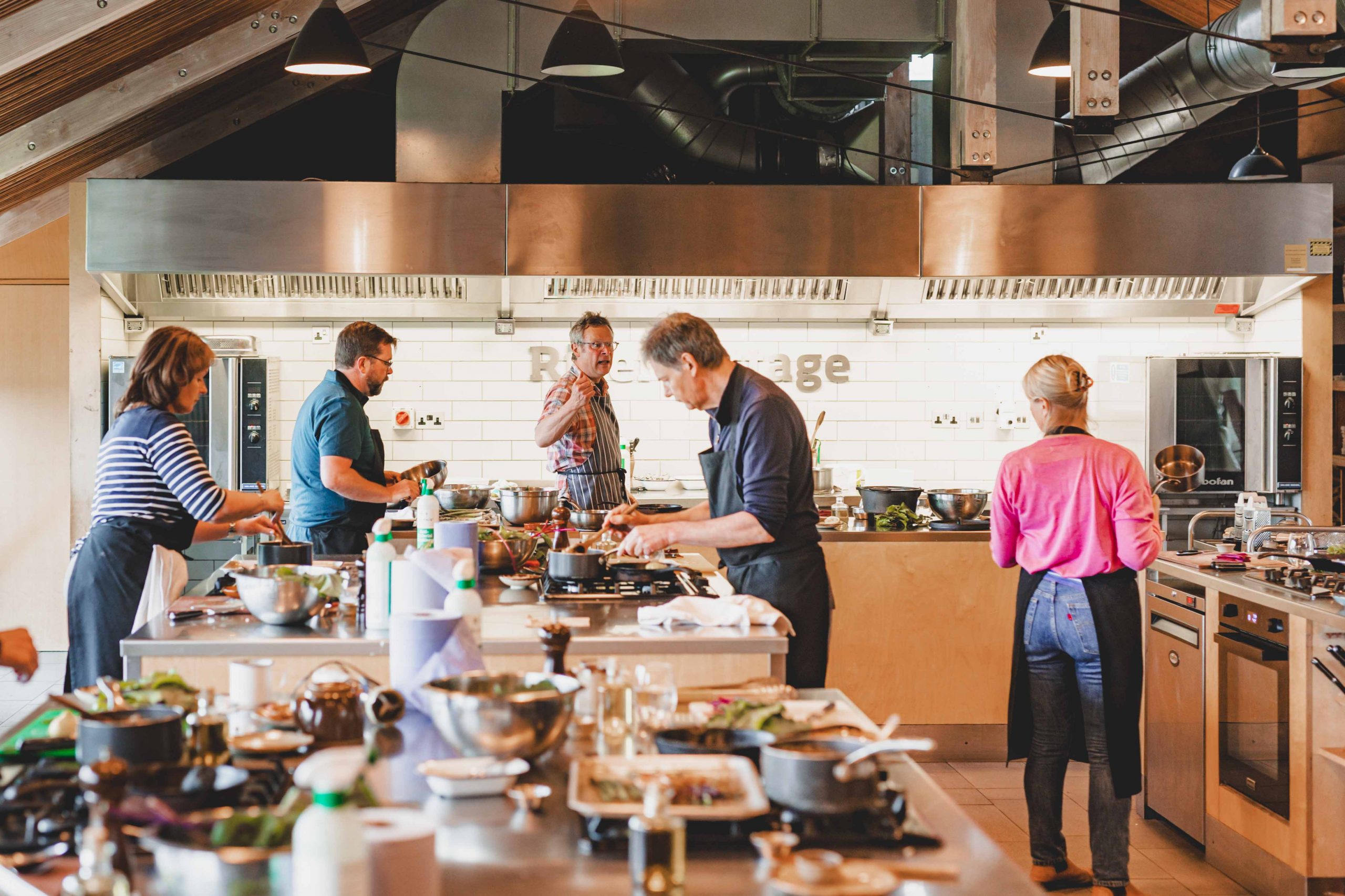 Cooking instructor and students discussing recipes and preparing ingredients during a hands-on culinary lesson